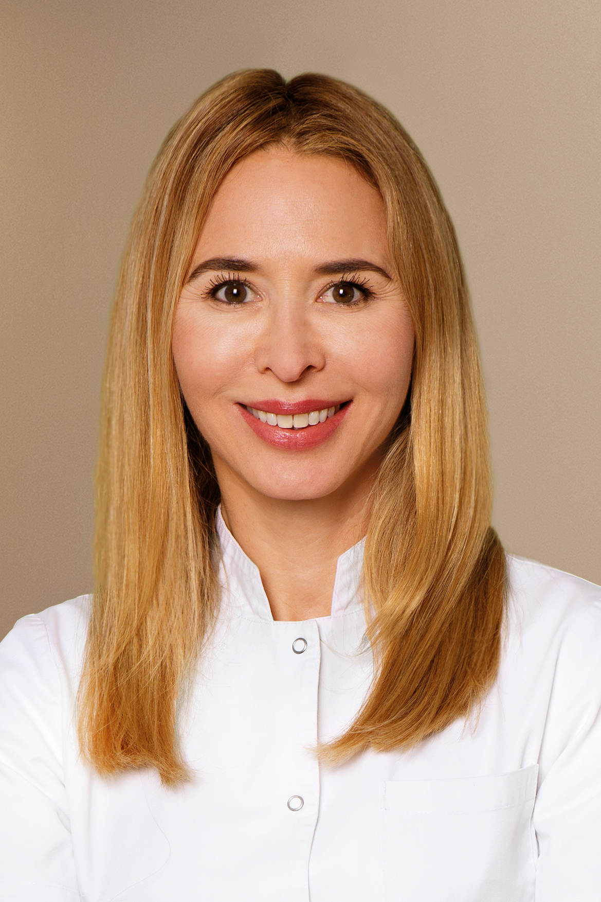 Eine lächelnde Frau mit glattem blonden Haar trägt einen weißen Arztkittel