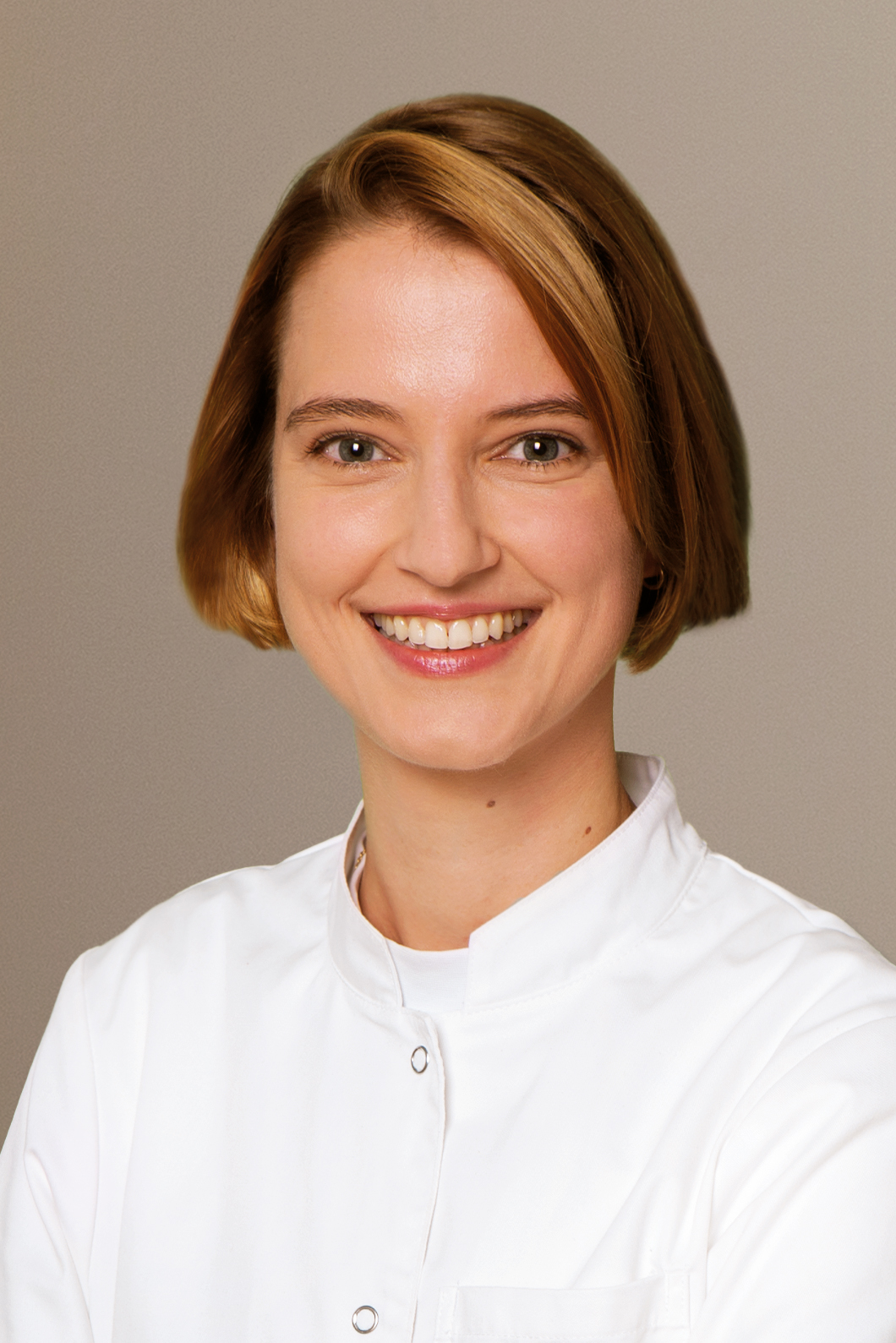 Eine lächelnde Frau mit kurzen blonden Haaren in einem weißen Arztkittel