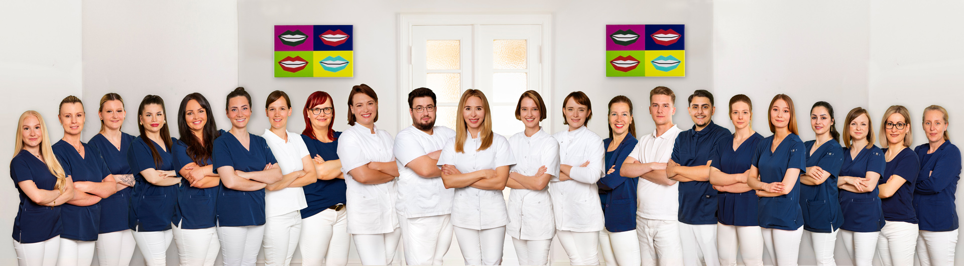 Ein Team aus Männern und Frauen in blauer und weißer Kleidung lächelt freundlich