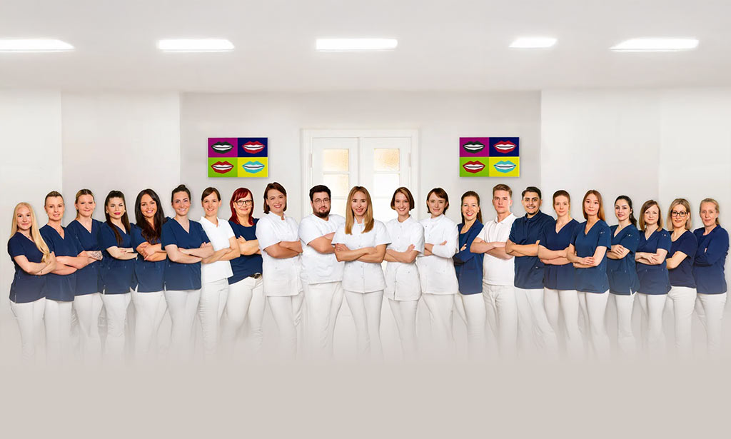 Eine Gruppe von zwanzig freundlich lächelnden Personen in blauer und weißer Kleidung